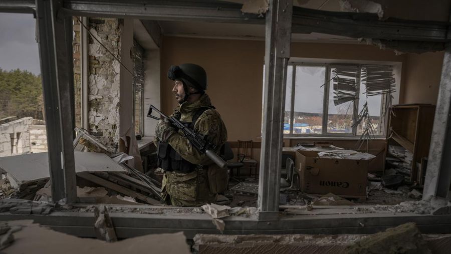 Seorang prajurit Ukraina berdiri di sebuah gedung yang rusak berat di Stoyanka, Ukraina, Minggu (27/3/2022). (AP Photo/Vadim Ghirda)