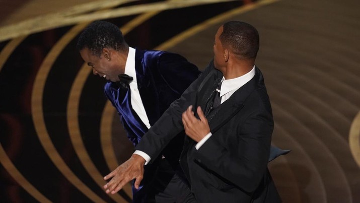 Will Smith (kanan) memukul presenter Chris Rock di atas panggung saat mempersembahkan penghargaan untuk film dokumenter terbaik di Oscar di Dolby Theatre di Los Angeles, Minggu (27/3/2022). (AP Photo/Chris Pizzello)