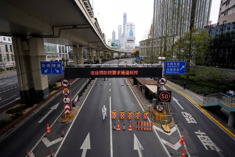 Polisi lalu lintas yang mengenakan pakaian pelindung memeriksa kendaraan sebelum terowongan underpass yang ditutup menyusul penyebaran Covid-19 di Shanghai, China, Senin (28/3/2022).  (Chinatopix Via AP)