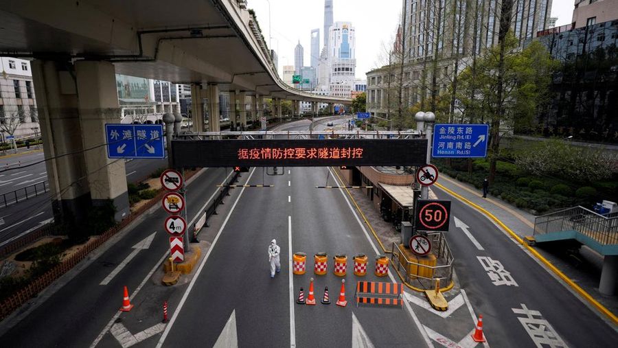 Seorang pekerja dengan pakaian pelindung berdiri di dekat pintu keluar terowongan yang mengarah ke daerah Pudong di seberang sungai Huangpu, saat penguncian atau lockdown secara bertahap akibat penyebaran Covid-19 di Shanghai, China, Minggu (28/3/2022) (REUTERS/Aly Song)