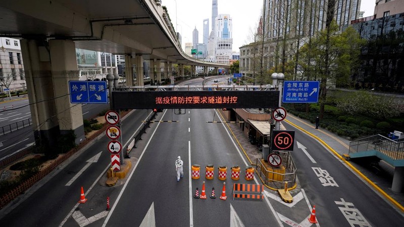 Polisi lalu lintas yang mengenakan pakaian pelindung memeriksa kendaraan sebelum terowongan underpass yang ditutup menyusul penyebaran Covid-19 di Shanghai, China, Senin (28/3/2022).  (Chinatopix Via AP)