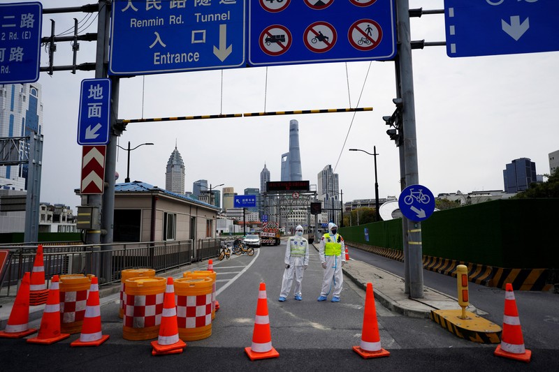Polisi lalu lintas yang mengenakan pakaian pelindung memeriksa kendaraan sebelum terowongan underpass yang ditutup menyusul penyebaran Covid-19 di Shanghai, China, Senin (28/3/2022).  (Chinatopix Via AP)