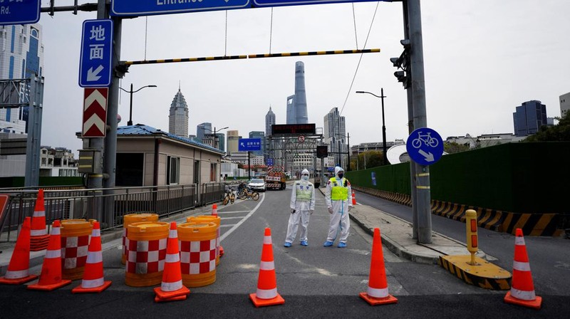 Polisi lalu lintas yang mengenakan pakaian pelindung memeriksa kendaraan sebelum terowongan underpass yang ditutup menyusul penyebaran Covid-19 di Shanghai, China, Senin (28/3/2022).  (Chinatopix Via AP)