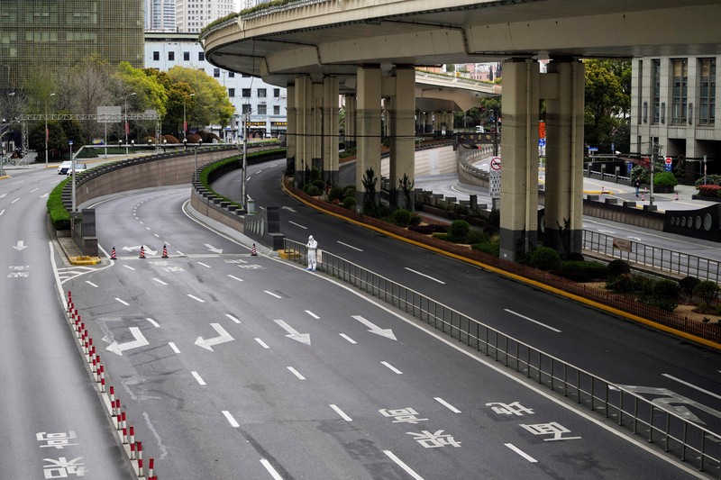 Polisi lalu lintas yang mengenakan pakaian pelindung memeriksa kendaraan sebelum terowongan underpass yang ditutup menyusul penyebaran Covid-19 di Shanghai, China, Senin (28/3/2022).  (Chinatopix Via AP)