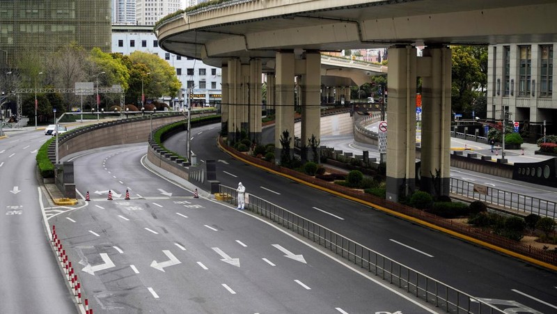 Polisi lalu lintas yang mengenakan pakaian pelindung memeriksa kendaraan sebelum terowongan underpass yang ditutup menyusul penyebaran Covid-19 di Shanghai, China, Senin (28/3/2022).  (Chinatopix Via AP)
