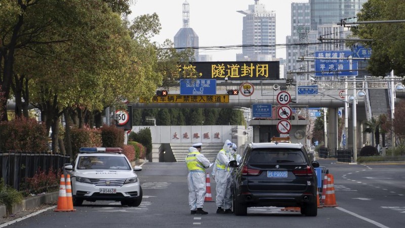 Polisi lalu lintas yang mengenakan pakaian pelindung memeriksa kendaraan sebelum terowongan underpass yang ditutup menyusul penyebaran Covid-19 di Shanghai, China, Senin (28/3/2022).  (Chinatopix Via AP)