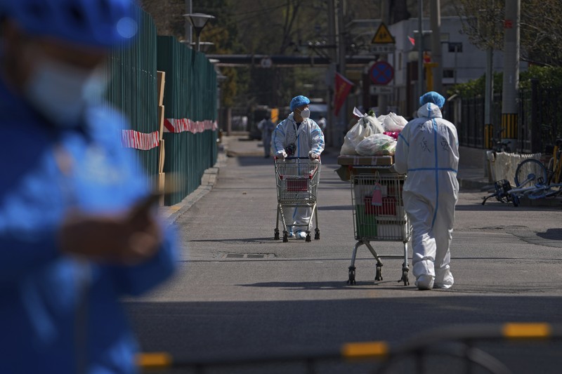 Suasana Shanghai Saat Lockdown China Polisi lalu lintas yang mengenakan pakaian pelindung memeriksa kendaraan sebelum terowongan underpass yang ditutup menyusul penyebaran Covid-19 di Shanghai, China, Senin (28/3/2022). (Chinatopix Via AP)