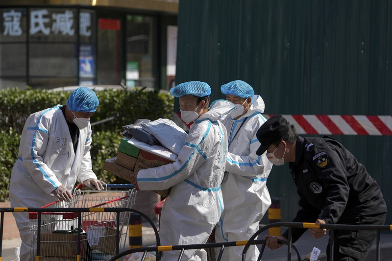 Polisi lalu lintas yang mengenakan pakaian pelindung memeriksa kendaraan sebelum terowongan underpass yang ditutup menyusul penyebaran Covid-19 di Shanghai, China, Senin (28/3/2022).  (Chinatopix Via AP)