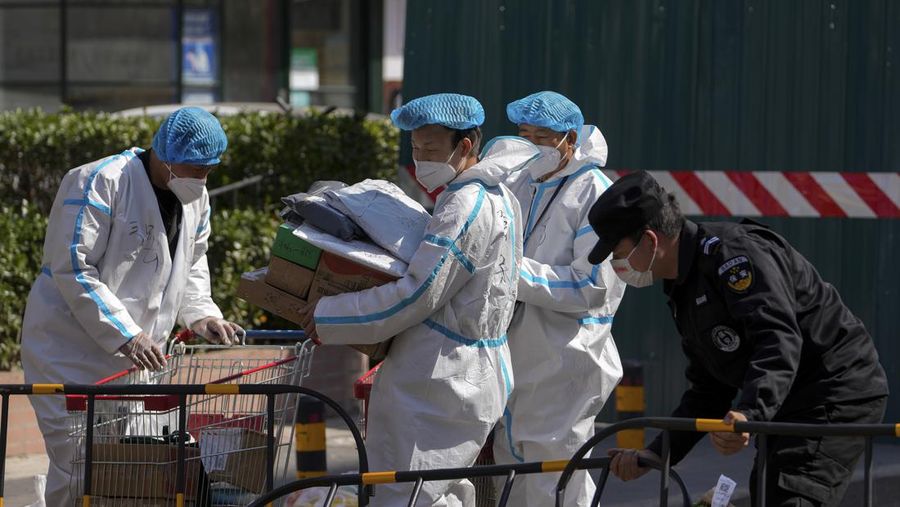 Polisi lalu lintas yang mengenakan pakaian pelindung memeriksa kendaraan sebelum terowongan underpass yang ditutup menyusul penyebaran Covid-19 di Shanghai, China, Senin (28/3/2022).  (Chinatopix Via AP)