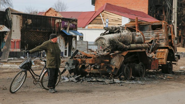 Kendaraan Militer Rusia Tank Rusia Hancur Terbakar di Ukraina Seorang penduduk setempat berdiri di samping kendaraan militer Rusia yang hancur, saat serangan Rusia ke Ukraina berlanjut di kota Trostianets, di wilayah Sumy, Ukraina, Senin (28/3/2022). (REUTERS/Oleg Pereverzev)