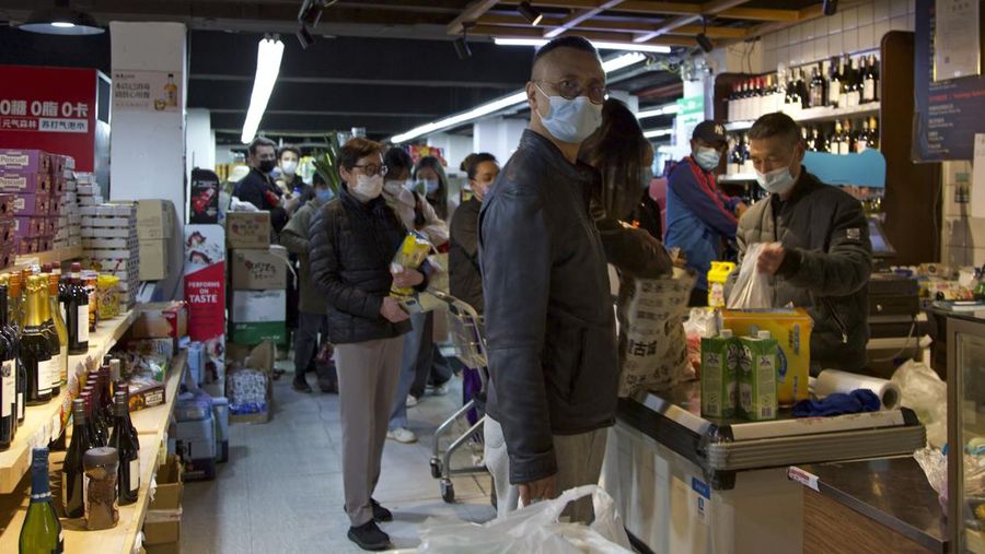 Pembeli berbaris untuk membayar belanjaannya di kasir saat pemberlakuan lockdown akibat meningkatnya penyebaran COVID-19 di sebuah supermarket di Shanghai, China, Selasa (29/3/2022). (AP Photo/Chen Si)
