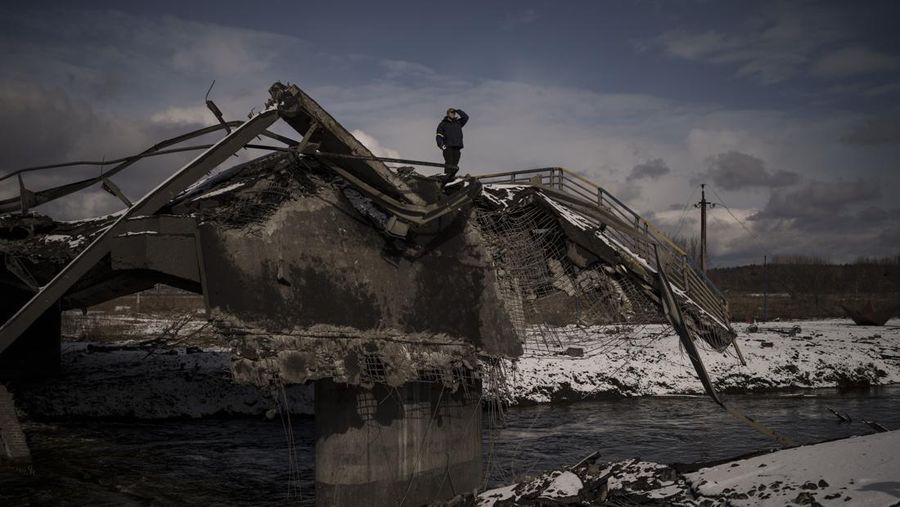 Seorang pria berdiri di atas jembatan yang hancur di Irpin, di pinggiran Kyiv, Ukraina, Selasa (8/3/2022). (AP Photo/Felipe Dana)