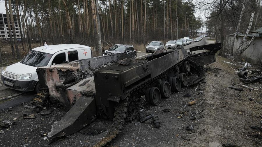 Mobil melewati tank Rusia yang hancur saat konvoi kendaraan yang mengevakuasi warga sipil meninggalkan Irpin, di pinggiran Kyiv, Ukraina