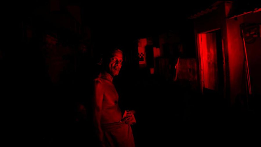 Seorang wanita bekerja di dalam sebuah toko yang terhubung dengan rumahnya selama pemadaman listrik di Kolombo, Sri Lanka, Rabu (30/3/2022). (REUTERS/Dinuka Liyanawatte)