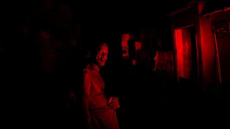 Seorang wanita bekerja di dalam sebuah toko yang terhubung dengan rumahnya selama pemadaman listrik di Kolombo, Sri Lanka, Rabu (30/3/2022). (REUTERS/Dinuka Liyanawatte)