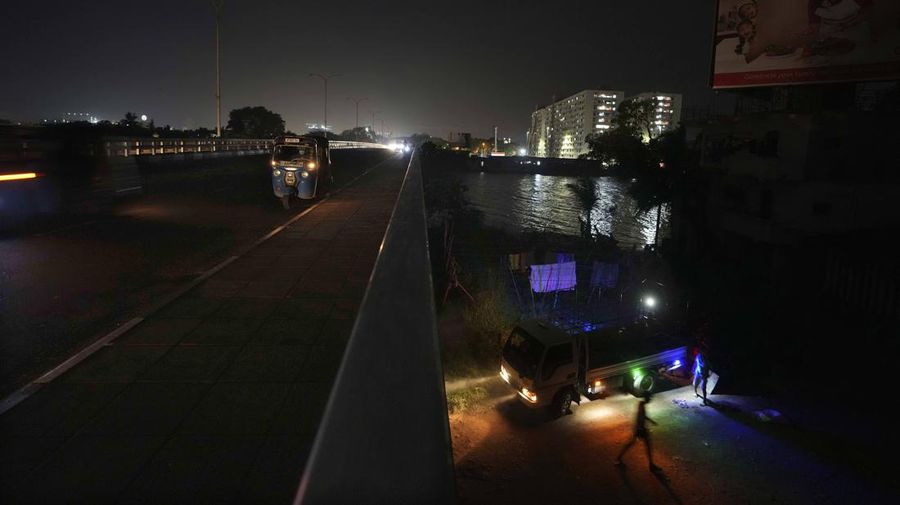 Jembatan persahabatan Jepang Sri Lanka, salah satu pintu masuk ke ibu kota Kolombo terlihat dalam kegelapan saat para pekerja memuat potongan besi ke truk selama pemadaman listrik di Peliyagoda, di pinggiran Kolombo, Sri Lanka, Kamis (3/3/2022). Sri Lanka mengalami pemadaman listrik berjam-jam setiap hari karena tidak dapat mengoperasikan turbin karena kekurangan bahan bakar. AP Photo/Eranga Jayawardena)