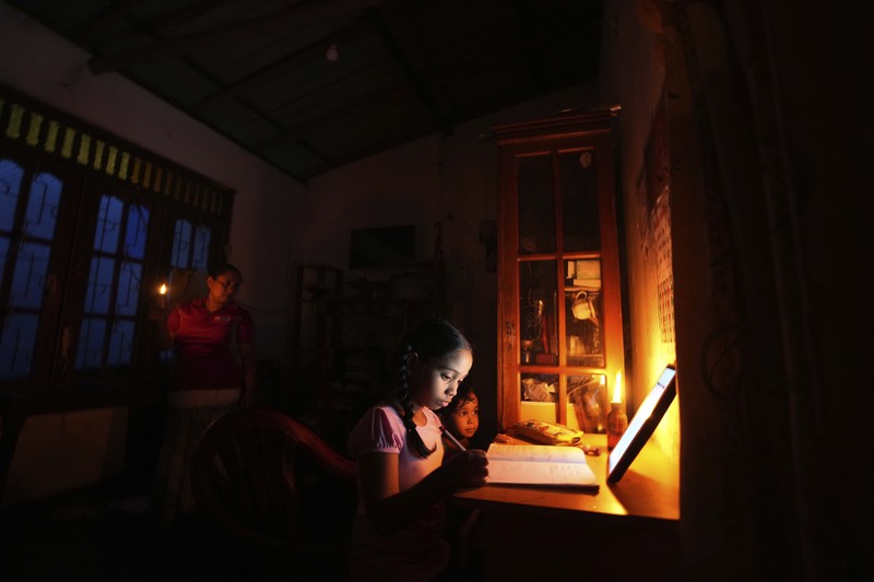 Seorang wanita bekerja di dalam sebuah toko yang terhubung dengan rumahnya selama pemadaman listrik di Kolombo, Sri Lanka, Rabu (30/3/2022). (REUTERS/Dinuka Liyanawatte)