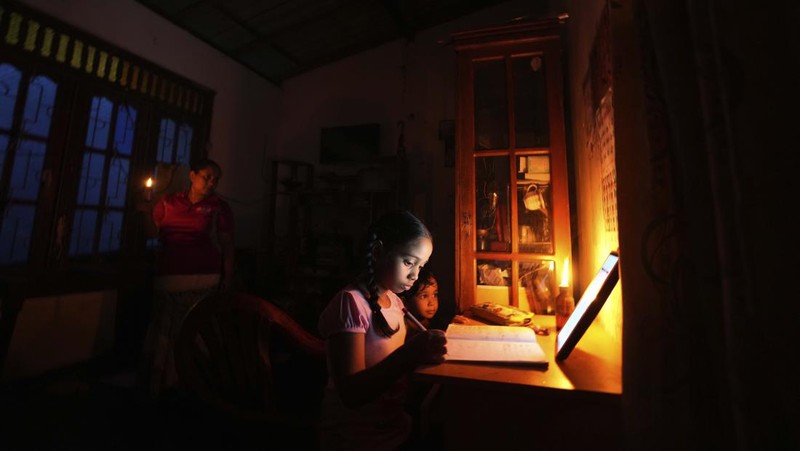 Seorang wanita bekerja di dalam sebuah toko yang terhubung dengan rumahnya selama pemadaman listrik di Kolombo, Sri Lanka, Rabu (30/3/2022). (REUTERS/Dinuka Liyanawatte)