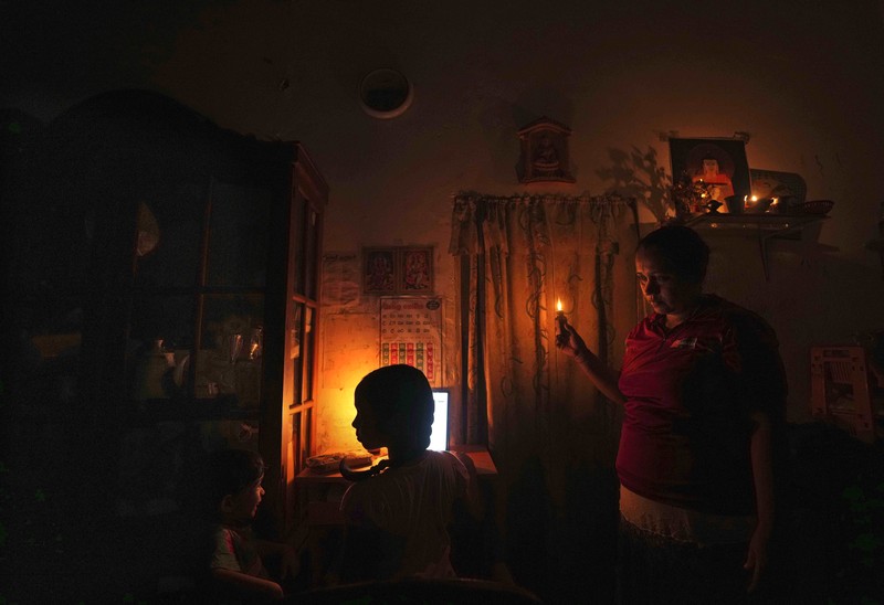 Seorang wanita bekerja di dalam sebuah toko yang terhubung dengan rumahnya selama pemadaman listrik di Kolombo, Sri Lanka, Rabu (30/3/2022). (REUTERS/Dinuka Liyanawatte)