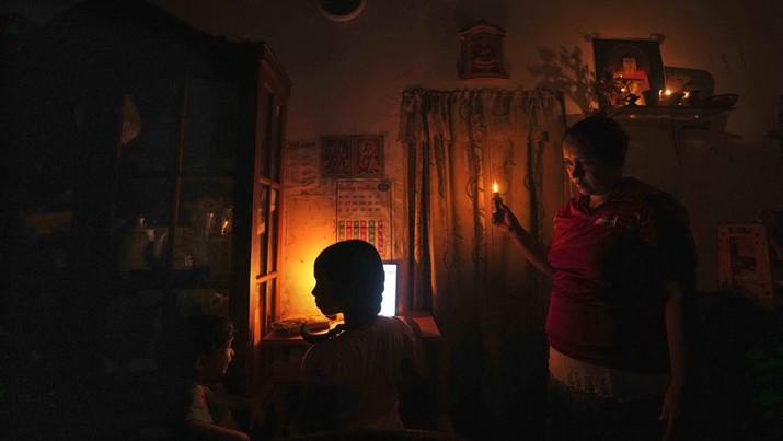Seorang ibu Sri Lanka berinteraksi dengan anak-anaknya saat mereka menghadiri pelajaran online dengan bantuan lampu minyak tanah selama pemadaman listrik di Kolombo, Sri Lanka, Jumat, (4/3/2022) Sri Lanka mengalami pemadaman listrik berjam-jam setiap hari karena tidak dapat mengoperasikan turbin karena kekurangan bahan bakar. (AP Photo/Eranga Jayawardena)