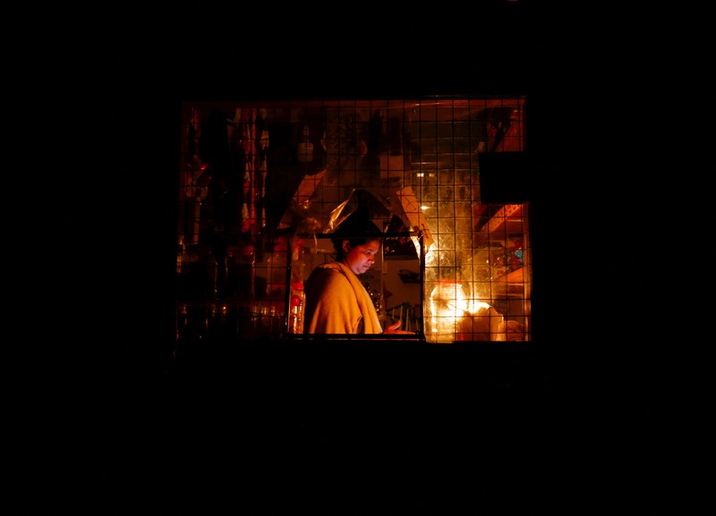 Seorang wanita bekerja di dalam sebuah toko yang terhubung dengan rumahnya selama pemadaman listrik di Kolombo, Sri Lanka, Rabu (30/3/2022). (REUTERS/Dinuka Liyanawatte)