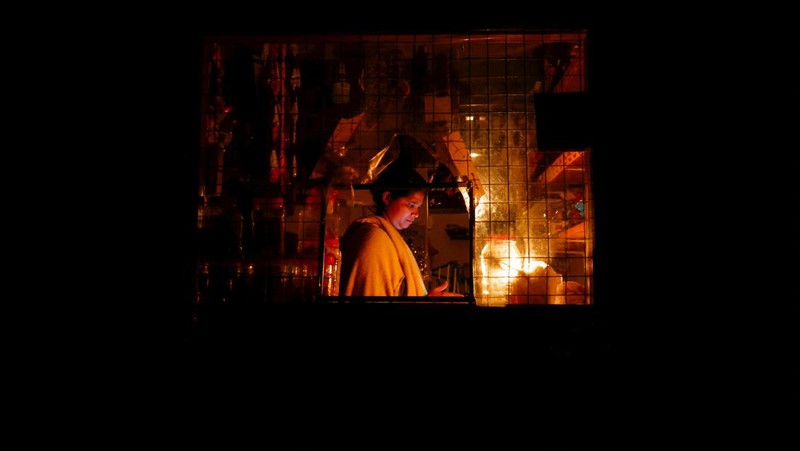 Seorang wanita bekerja di dalam sebuah toko yang terhubung dengan rumahnya selama pemadaman listrik di Kolombo, Sri Lanka, Rabu (30/3/2022). (REUTERS/Dinuka Liyanawatte)
