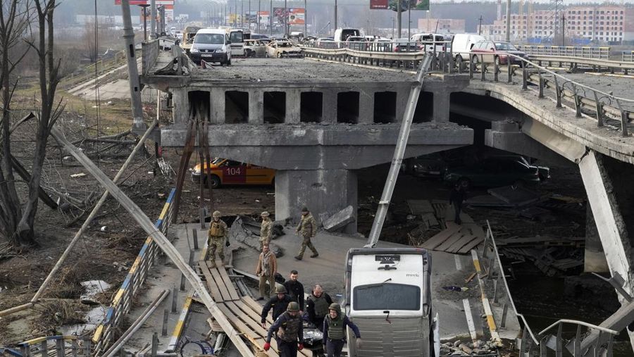 Tentara Ukraina membawa mayat seorang warga sipil yang tewas oleh pasukan Rusia di atas jembatan yang hancur di Irpin dekat Kyiv, Ukraina, Kamis (31/3/2022).  (AP Photo/Efrem Lukatsky)