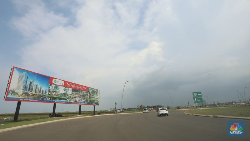 Kendaraan melintas di depan reklame di kawasan Pantai Indah Kapuk (PIK) 2, Selasa (5/3/2022). (CNBC Indonesia/Andrean Kristianto)