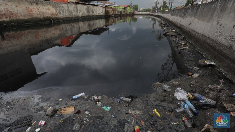 Kendaraan melintas di samping kali yang berwarna hitam di Kamal Muara, Jakarta Utara, Selasa (5/3/2022). (CNBC Indonesia/Andrean Kristianto)