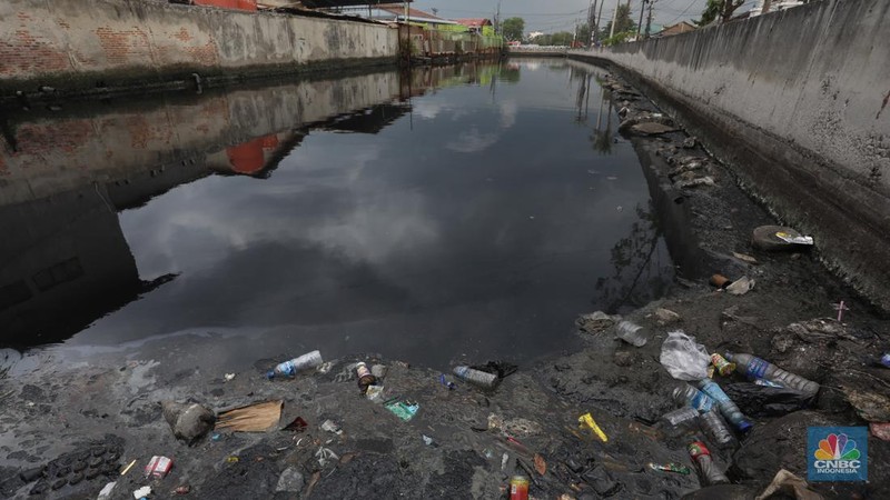 Kendaraan melintas di samping kali yang berwarna hitam di Kamal Muara, Jakarta Utara, Selasa (5/3/2022). (CNBC Indonesia/Andrean Kristianto)