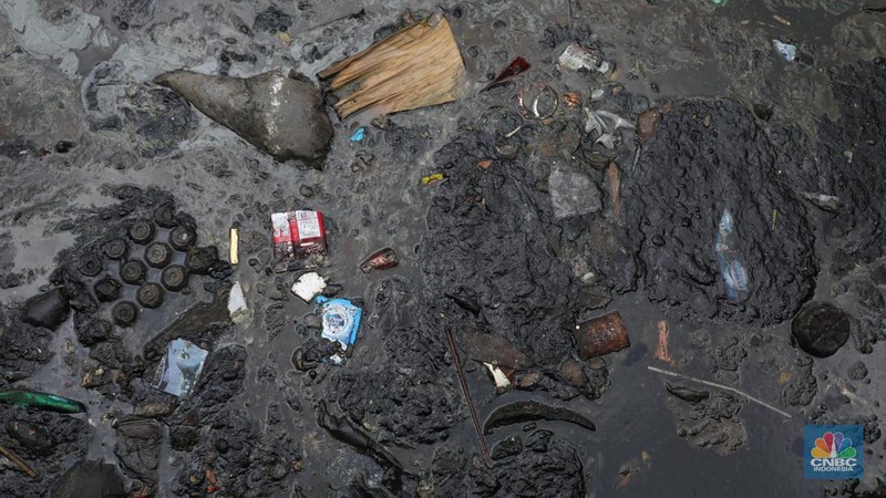Kendaraan melintas di samping kali yang berwarna hitam di Kamal Muara, Jakarta Utara, Selasa (5/3/2022). (CNBC Indonesia/Andrean Kristianto)