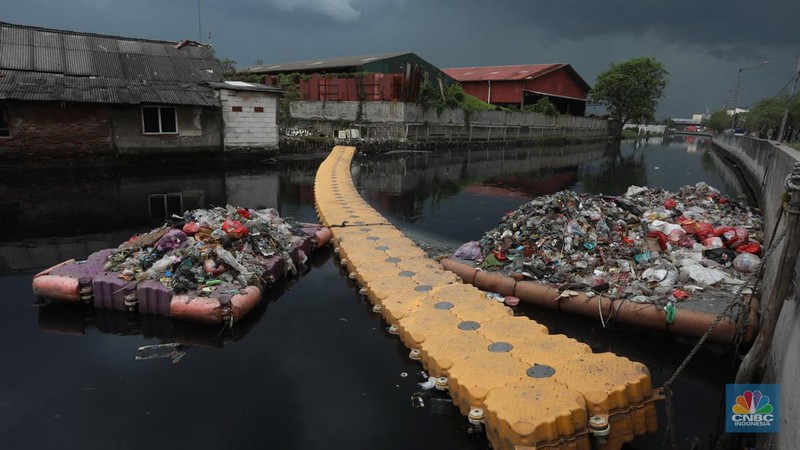 Kendaraan melintas di samping kali yang berwarna hitam di Kamal Muara, Jakarta Utara, Selasa (5/3/2022). (CNBC Indonesia/Andrean Kristianto)