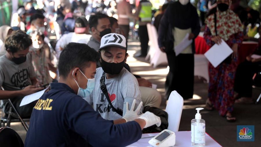 Petugas menyuntikkan vaksin Covid-19 dosis ketiga (booster) di Lobby Pasar Induk Kramat Jati, Jakarta, Rabu, 6 April 2022. (CNBC Indonesia/Muhammad Sabki)