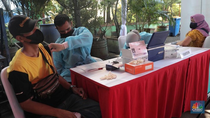 Petugas menyuntikkan vaksin Covid-19 dosis ketiga (booster) di Lobby Pasar Induk Kramat Jati, Jakarta, Rabu, 6 April 2022. (CNBC Indonesia/Muhammad Sabki)