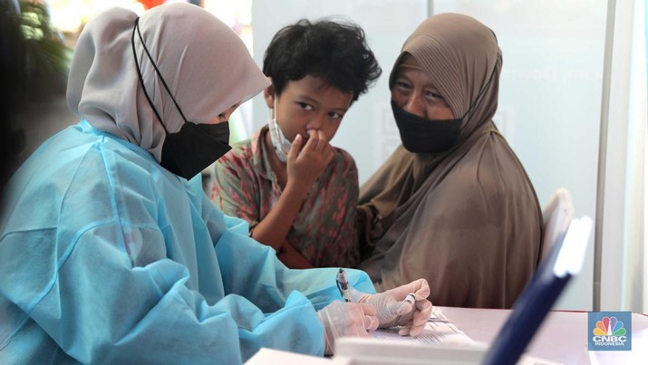 Petugas menyuntikkan vaksin Covid-19 dosis ketiga (booster) di Lobby Pasar Induk Kramat Jati, Jakarta, Rabu, 6 April 2022. (CNBC Indonesia/Muhammad Sabki)