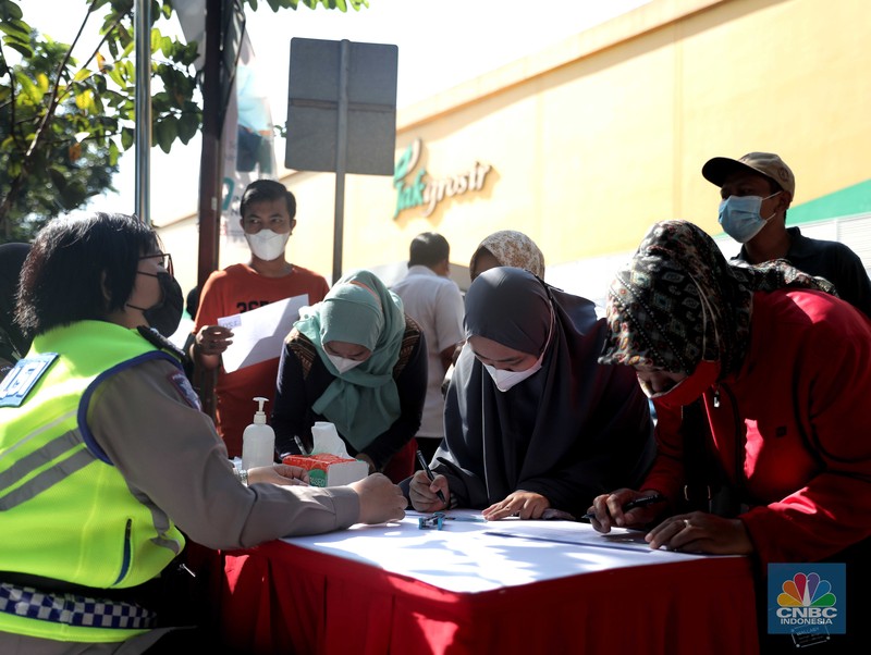 Petugas menyuntikkan vaksin Covid-19 dosis ketiga (booster) di Lobby Pasar Induk Kramat Jati, Jakarta, Rabu, 6 April 2022. (CNBC Indonesia/Muhammad Sabki)