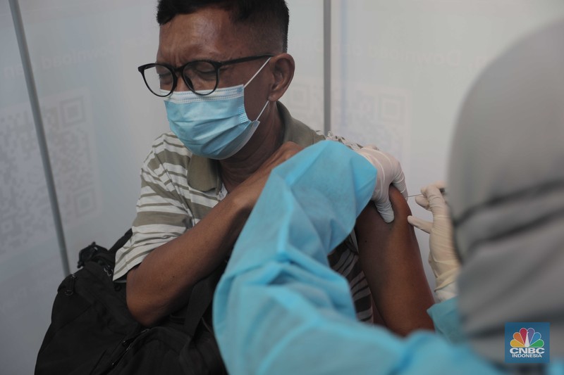 Petugas menyuntikkan vaksin Covid-19 dosis ketiga (booster) di Lobby Pasar Induk Kramat Jati, Jakarta, Rabu, 6 April 2022. (CNBC Indonesia/Muhammad Sabki)