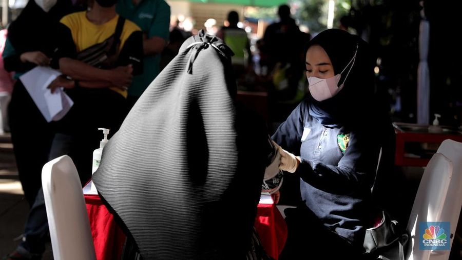 Petugas menyuntikkan vaksin Covid-19 dosis ketiga (booster) di Lobby Pasar Induk Kramat Jati, Jakarta, Rabu, 6 April 2022. (CNBC Indonesia/Muhammad Sabki)