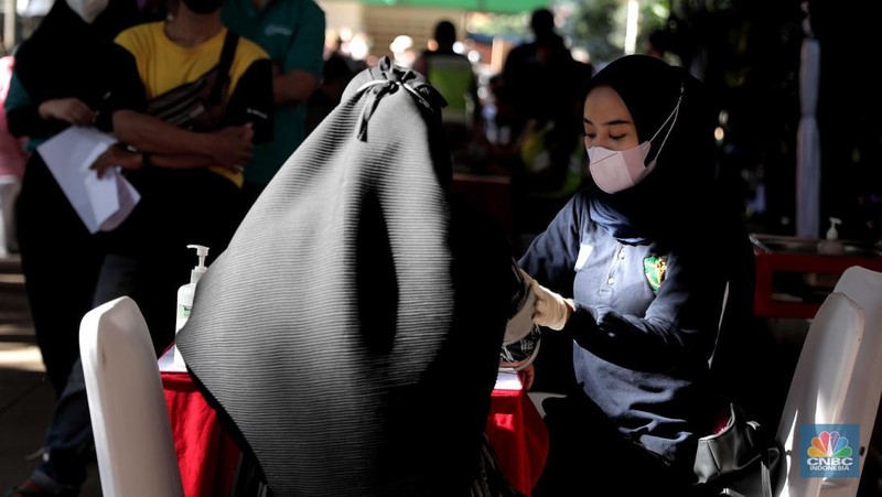 Petugas menyuntikkan vaksin Covid-19 dosis ketiga (booster) di Lobby Pasar Induk Kramat Jati, Jakarta, Rabu, 6 April 2022. (CNBC Indonesia/Muhammad Sabki)