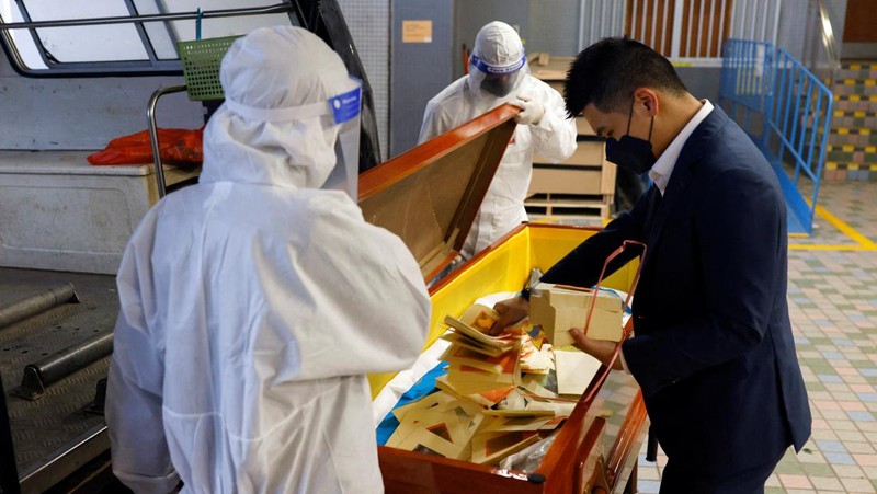 Petugas memindahkan  jenazah ke dalam kontainer berpendingin ksaat kamar jenazah kehabisan ruang di tengah wabah penyakit coronavirus (COVID-19) di luar rumah duka di Hong Kong,  Sabtu (5/3/2022). (REUTERS/Tyrone Siu)