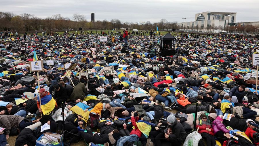 Orang-orang berbaring di tanah untuk melambangkan orang-orang yang tewas dalam perang di Ukraina selama demonstrasi menentang invasi Rusia ke Ukraina, di depan gedung Reichstag di Berlin, Jerman, Rabu, 6 April 2022. (REUTERS/CHRISTIAN MANG)