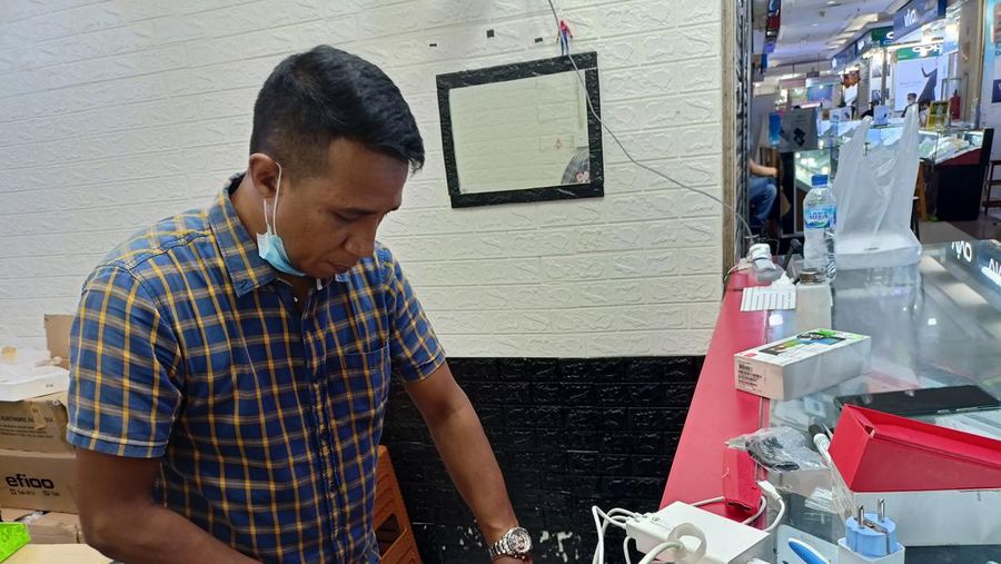 Pemilik toko di ITC Roxy sedang membungkus barang yang dijual lewat situs belanja online.