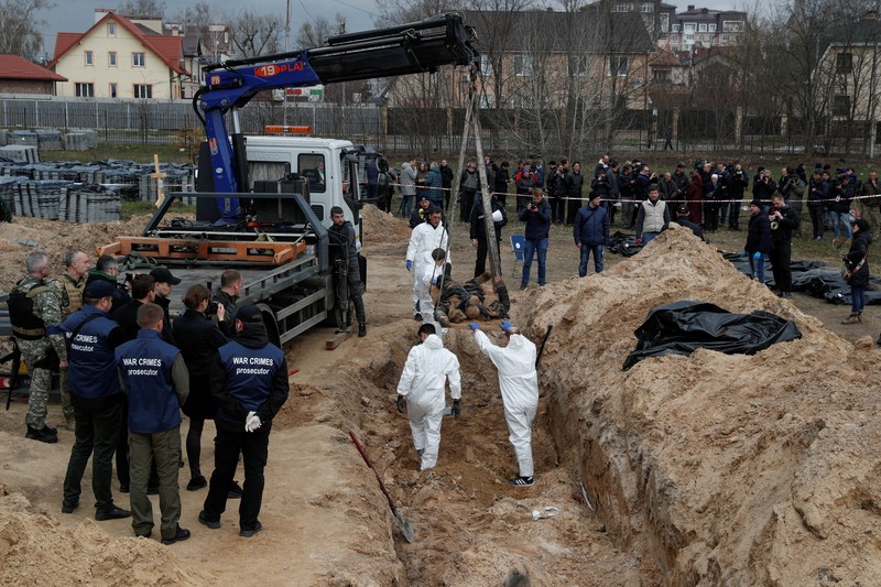 Tim forensik menggali mayat warga sipil yang menurut pejabat Ukraina tewas saat serangan Rusia  dan kemudian dimakamkan di kuburan massal di kota Bucha, di luar Kyiv, Ukraina, Jumat (8/4/2022). (REUTERS/Valentyn Ogirenko)