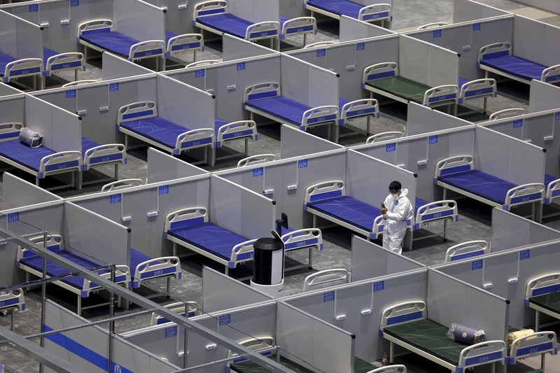 Seseorang dengan pakaian pelindung meemanjat barikade yang dipasang di sekitar area tertutup, selama penguncian untuk mengekang penyebaran penyakit coronavirus (COVID-19) di Shanghai, China, Senin (11/4/2022). (REUTERS/Aly Song)