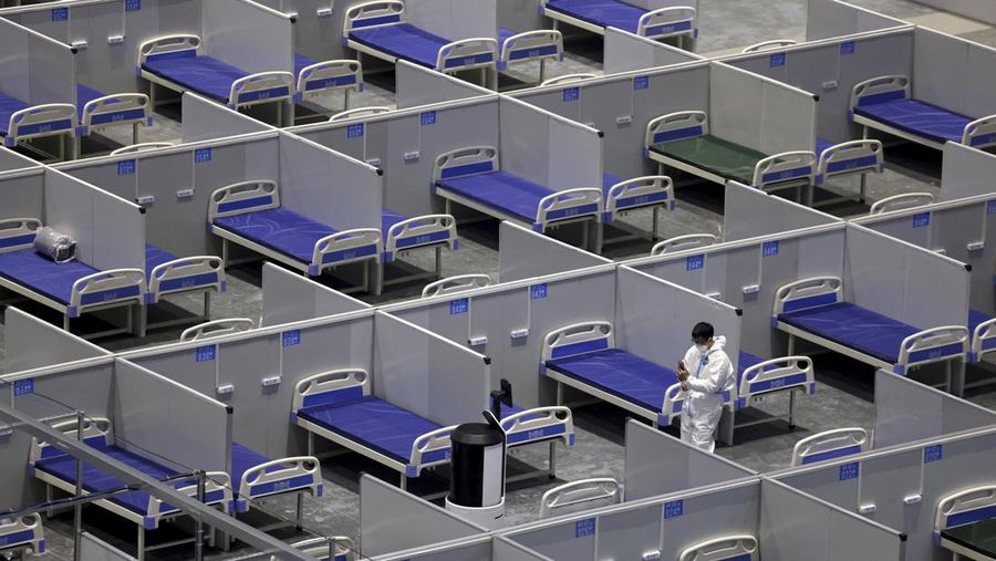 Seseorang dengan pakaian pelindung meemanjat barikade yang dipasang di sekitar area tertutup, selama penguncian untuk mengekang penyebaran penyakit coronavirus (COVID-19) di Shanghai, China, Senin (11/4/2022). (REUTERS/Aly Song)