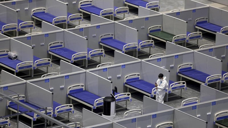 Seseorang dengan pakaian pelindung meemanjat barikade yang dipasang di sekitar area tertutup, selama penguncian untuk mengekang penyebaran penyakit coronavirus (COVID-19) di Shanghai, China, Senin (11/4/2022). (REUTERS/Aly Song)
