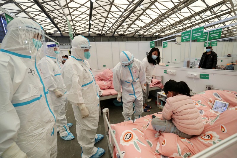 Seseorang dengan pakaian pelindung meemanjat barikade yang dipasang di sekitar area tertutup, selama penguncian untuk mengekang penyebaran penyakit coronavirus (COVID-19) di Shanghai, China, Senin (11/4/2022). (REUTERS/Aly Song)