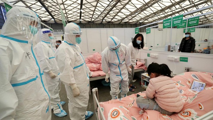 Rumah Sakit Darurat Covid-19 Saat Lockdown di Shanghai, China Pekerja medis dengan pakaian pelindung memeriksa pasien anak-anak saat mereka melakukan pemeriksaan di bangsal Shanghai New International Exhibition Hall, yang telah diubah menjadi rumah sakit darurat untuk penyakit virus corona (COVID-19), di Shanghai, China, Sabtu (9/4/2022). (China Daily via REUTERS)