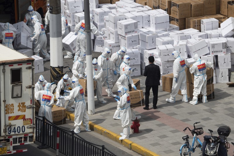 Seseorang dengan pakaian pelindung meemanjat barikade yang dipasang di sekitar area tertutup, selama penguncian untuk mengekang penyebaran penyakit coronavirus (COVID-19) di Shanghai, China, Senin (11/4/2022). (REUTERS/Aly Song)