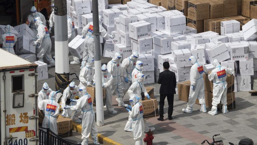 Seseorang dengan pakaian pelindung meemanjat barikade yang dipasang di sekitar area tertutup, selama penguncian untuk mengekang penyebaran penyakit coronavirus (COVID-19) di Shanghai, China, Senin (11/4/2022). (REUTERS/Aly Song)